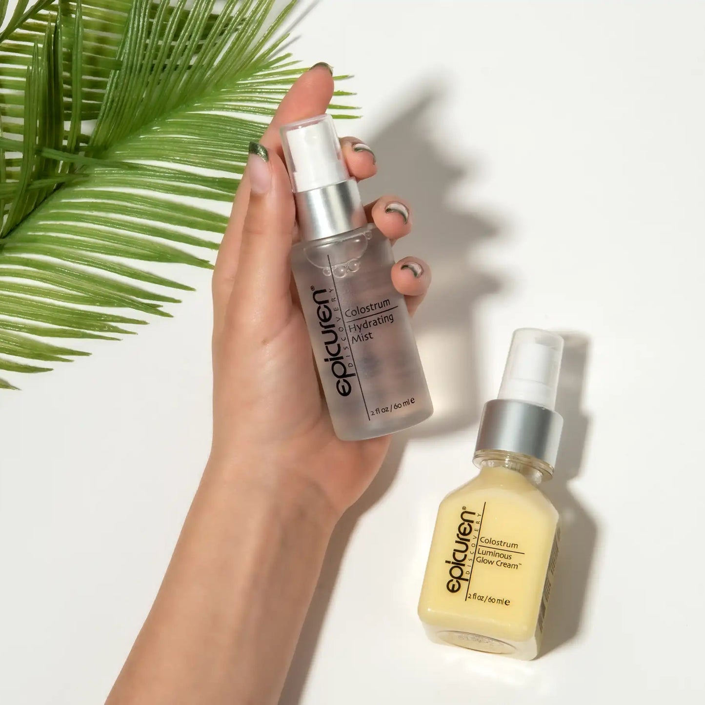 Hand holding a bottle of eplufeuze skincare product with another bottle on a white background