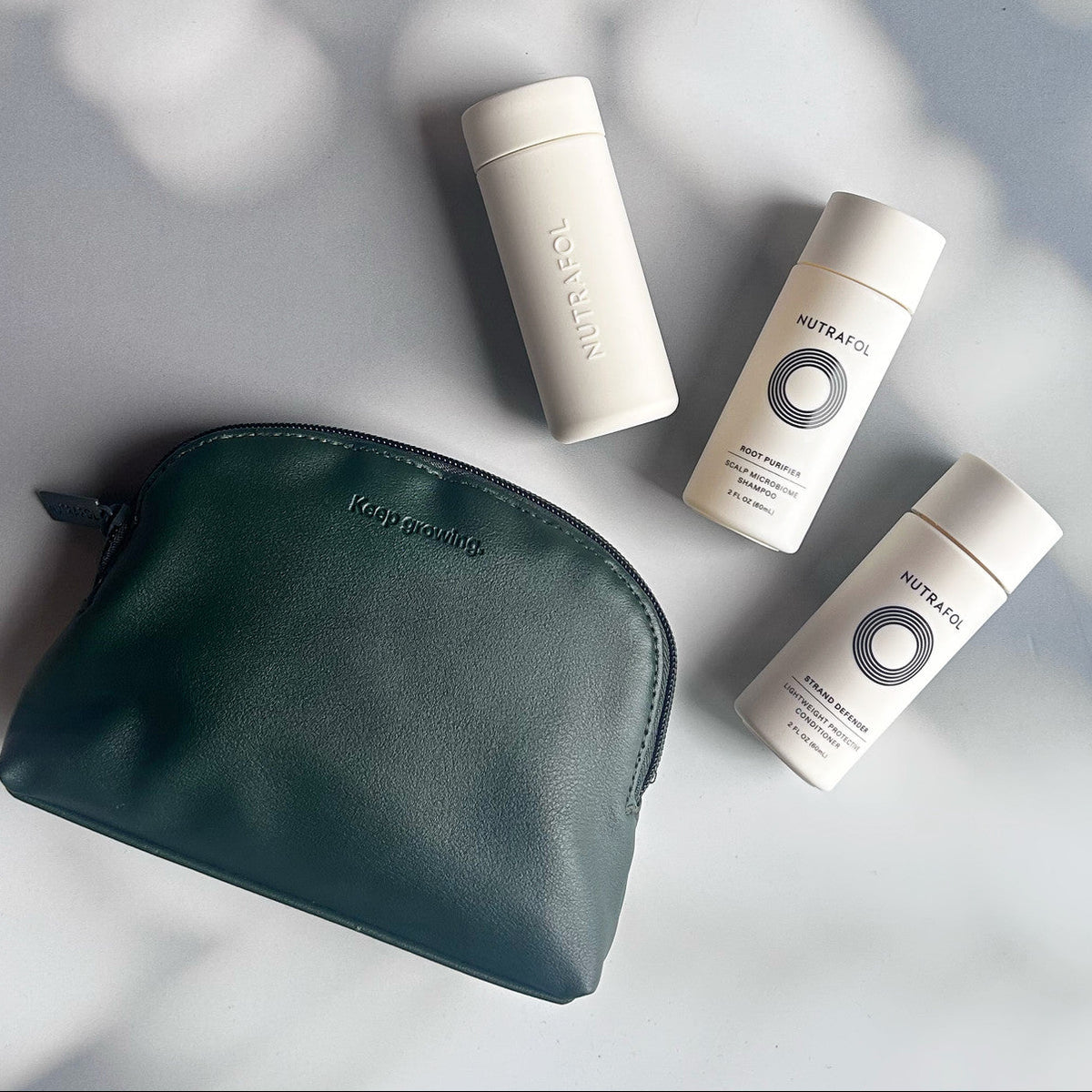 Nutrafol hair care products with a green pouch on a light gray background