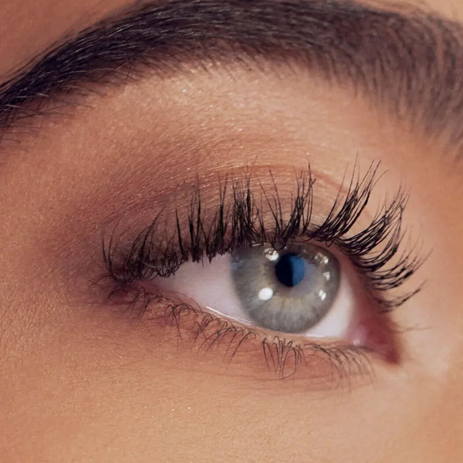 Close-up of a person's eye with long eyelashes and smoky eye makeup.