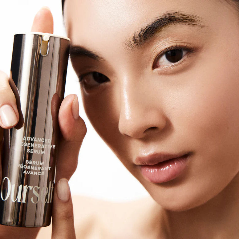 Woman holding a skincare product labeled 'Ourself' against a neutral background