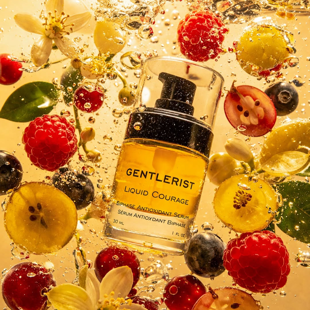Gentlerist serum bottle surrounded by fruits and flowers on a reflective surface