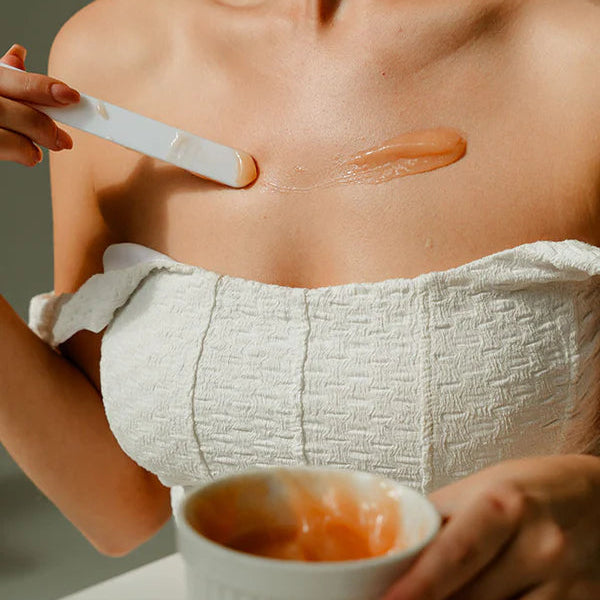 Person applying a cosmetic product to their shoulder with a brush.