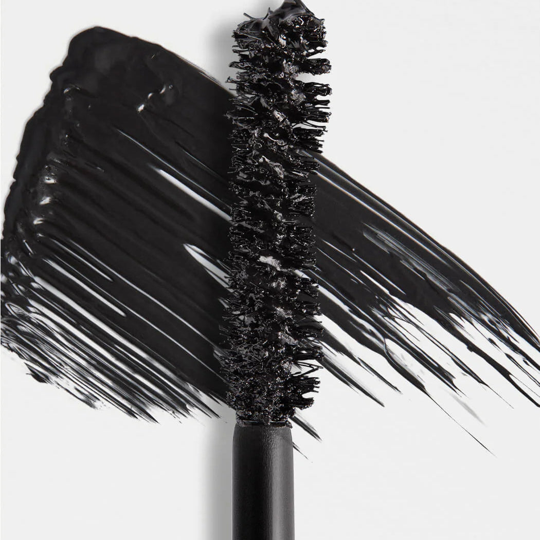 Black mascara wand with mascara on a white background