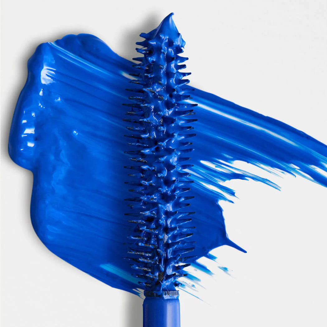 Blue mascara brush with blue mascara on a white background