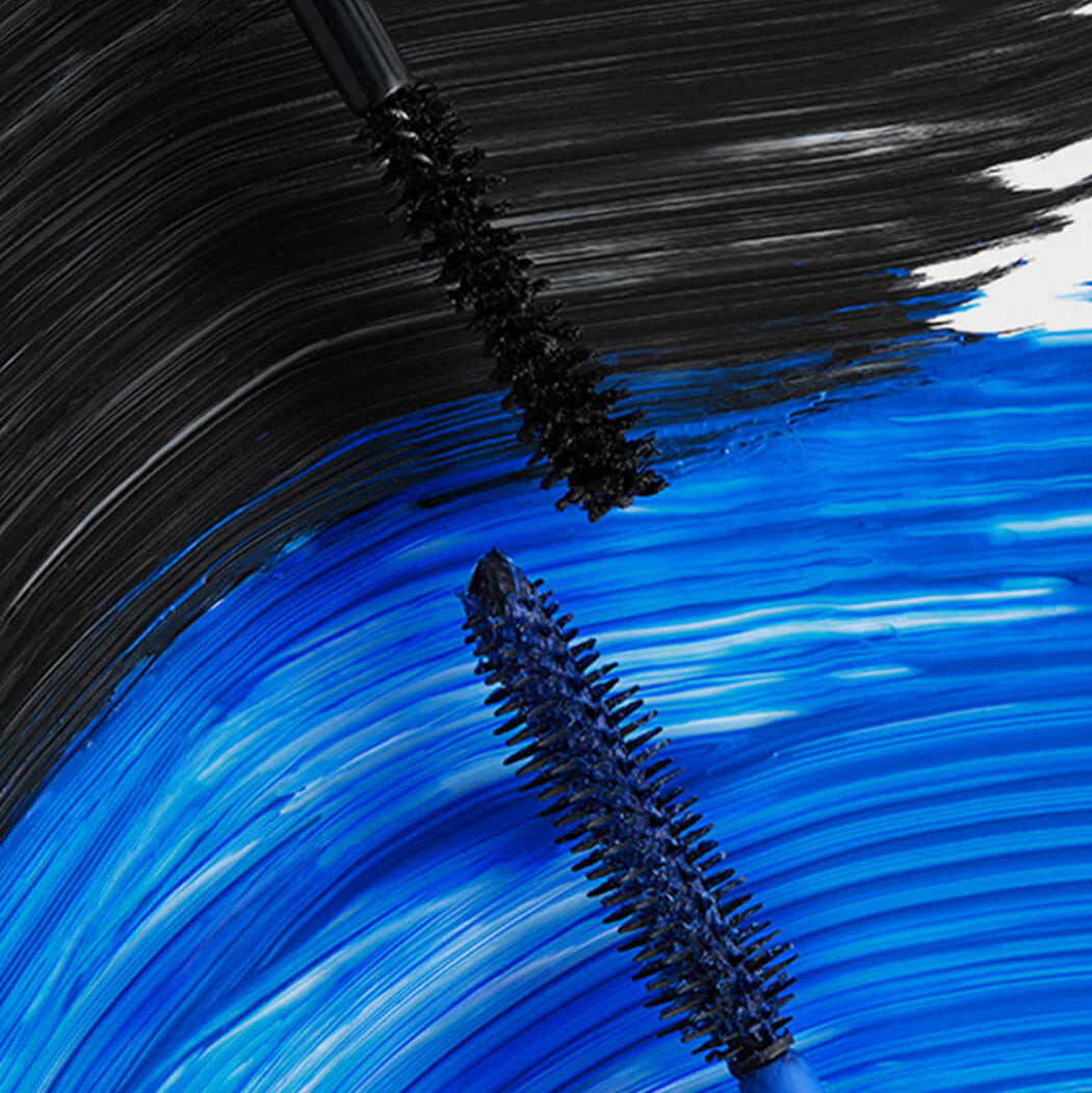 Close-up of mascara brushes with black and blue bristles on a textured background