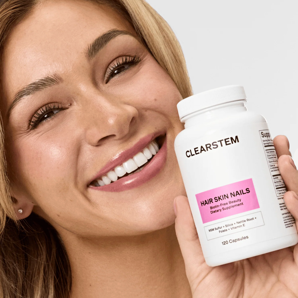 Woman holding a Clearstem supplement bottle with a white background