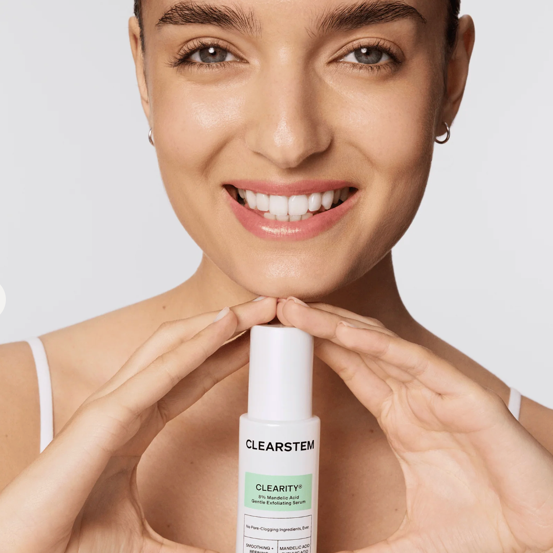 Woman holding a CLEARSTEM skincare product against a plain background
