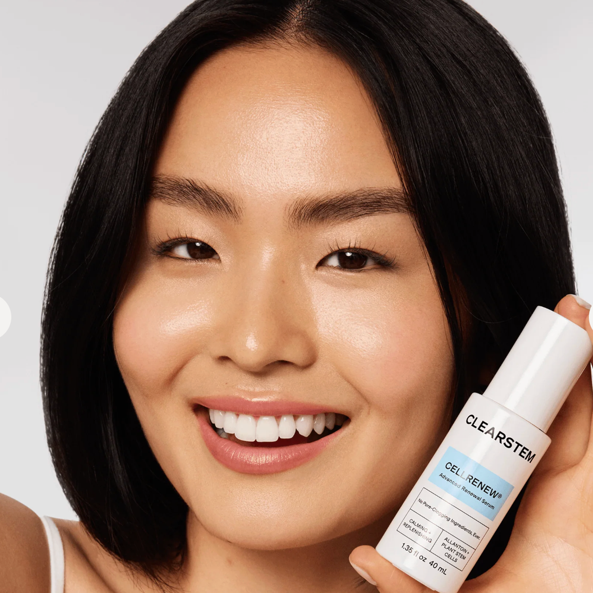 Woman holding a CLEARSTEM skincare product against a neutral background