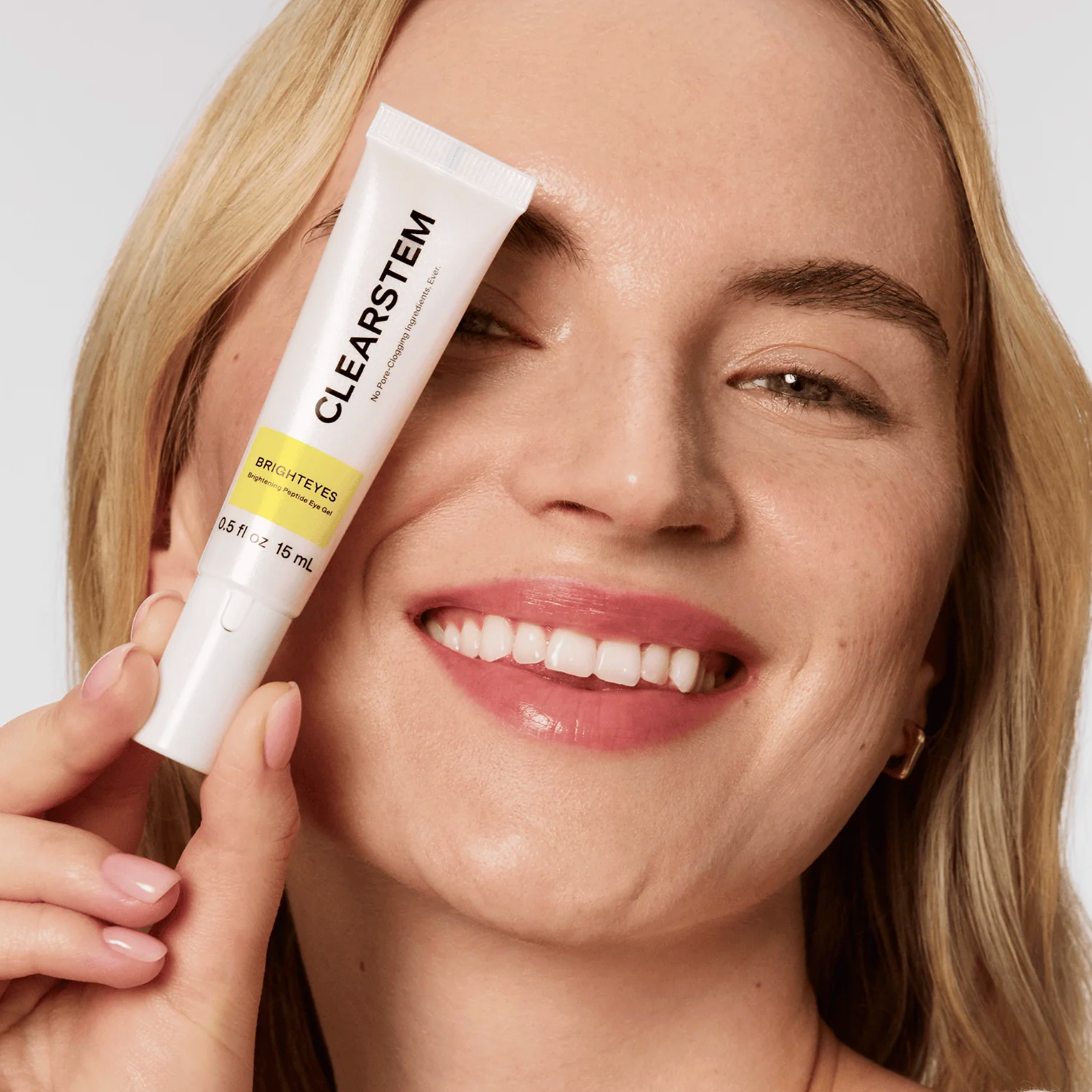 Woman holding a tube of Clearstem skincare product near her face.