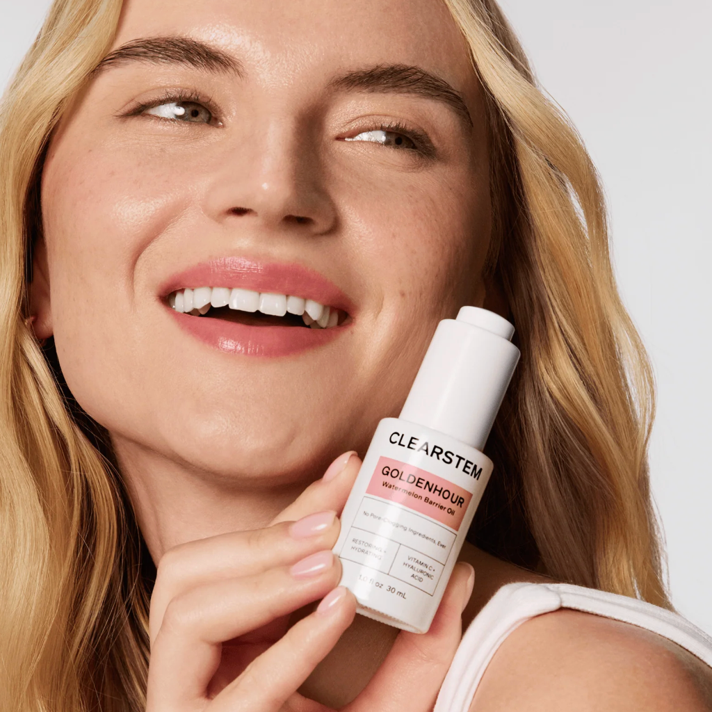 Woman holding a skincare product with a visible brand label against a neutral background