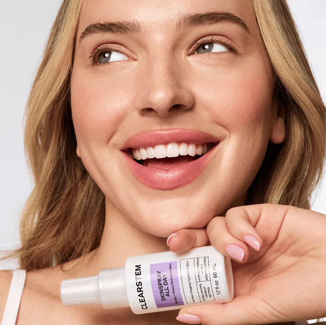 Woman holding a skincare product with a plain background
