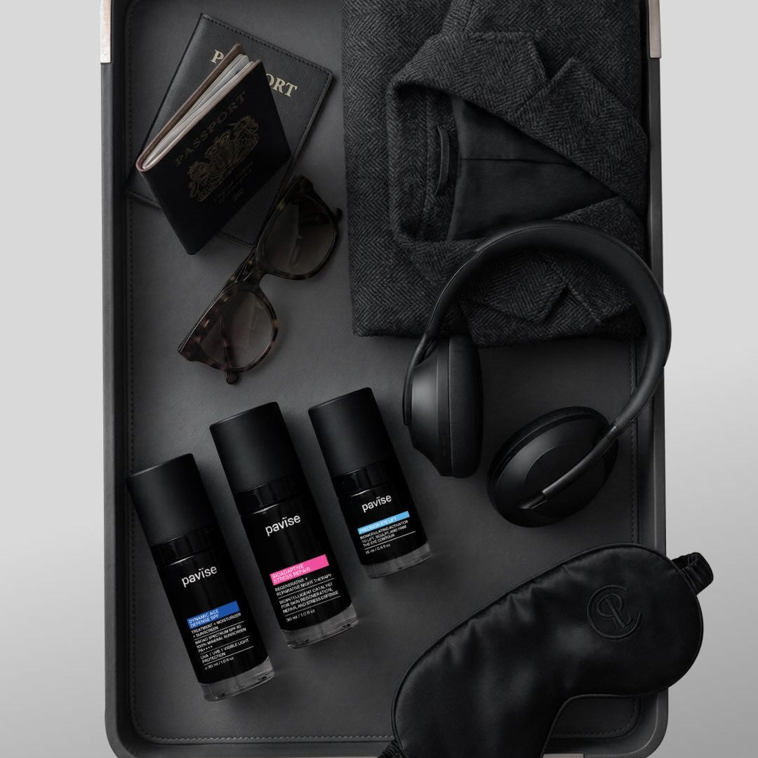 Collection of travel items including bottles, sunglasses, socks, headphones, and a sleep mask on a tray.