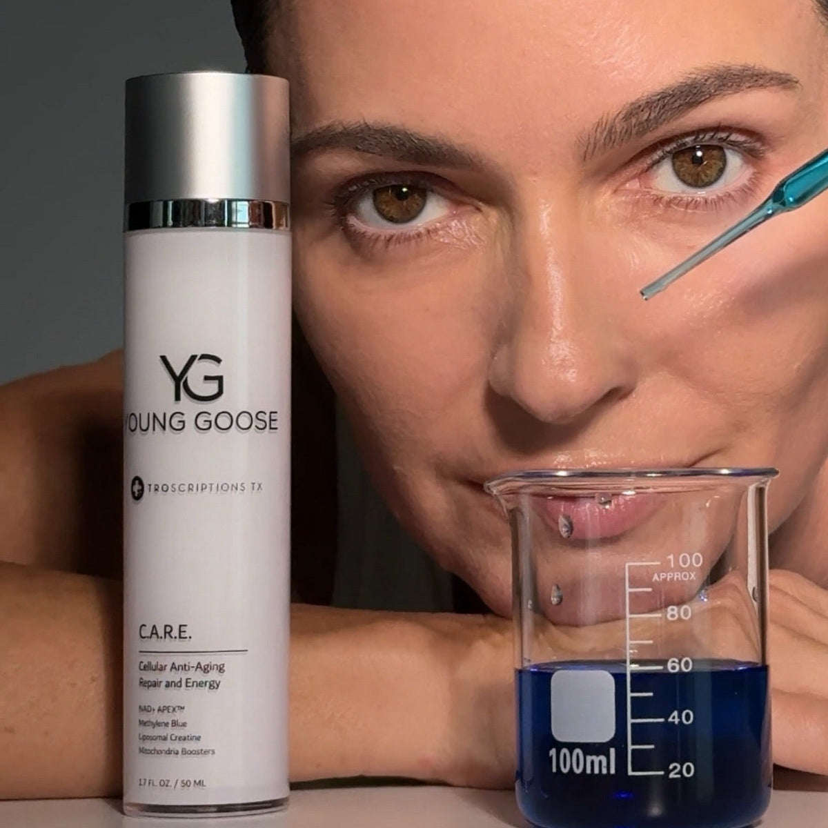 A close-up beauty shot showing a woman's face beside a white Young Goose Care skincare bottle and a glass beaker filled with blue liquid, with a pipette touching her eye area.