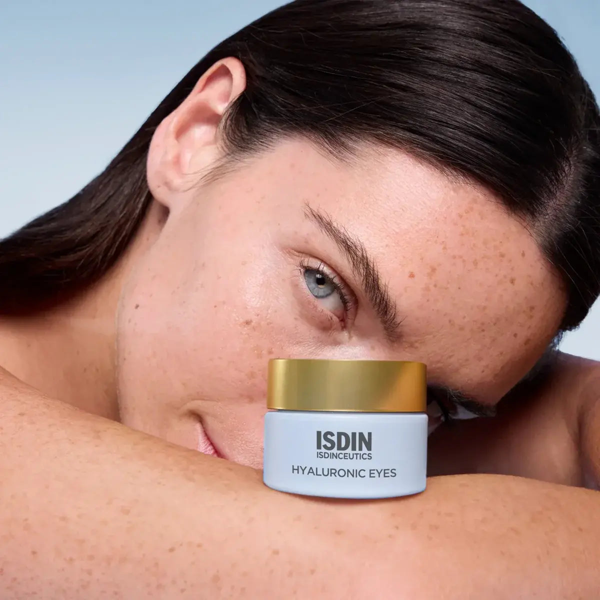 Woman holding an ISDIN skincare product with a blue background
