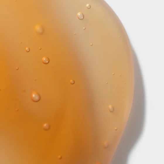 Close-up of a yellowish liquid with bubbles on a light gray background