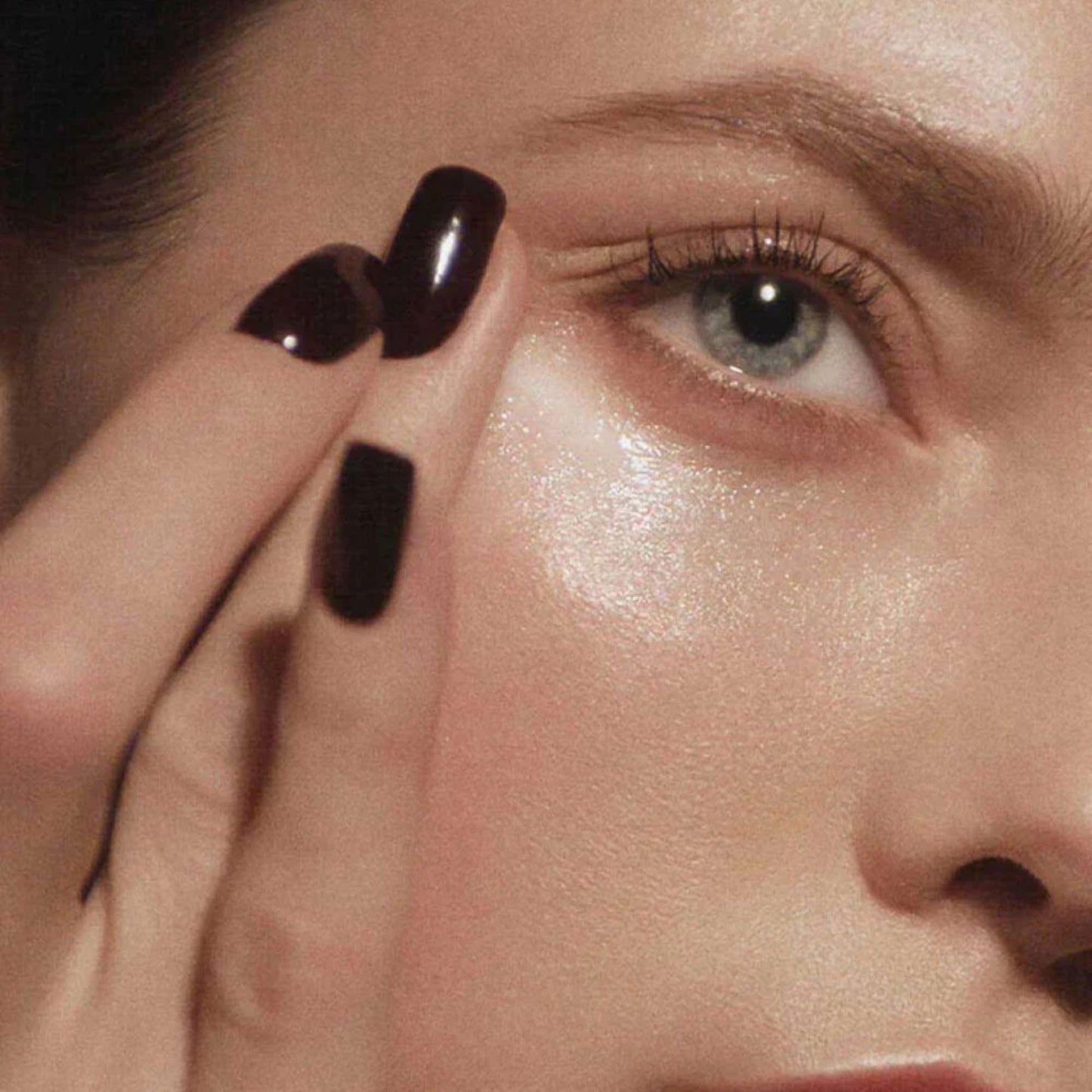 Close-up of a person applying eye cream to their upper lash line.