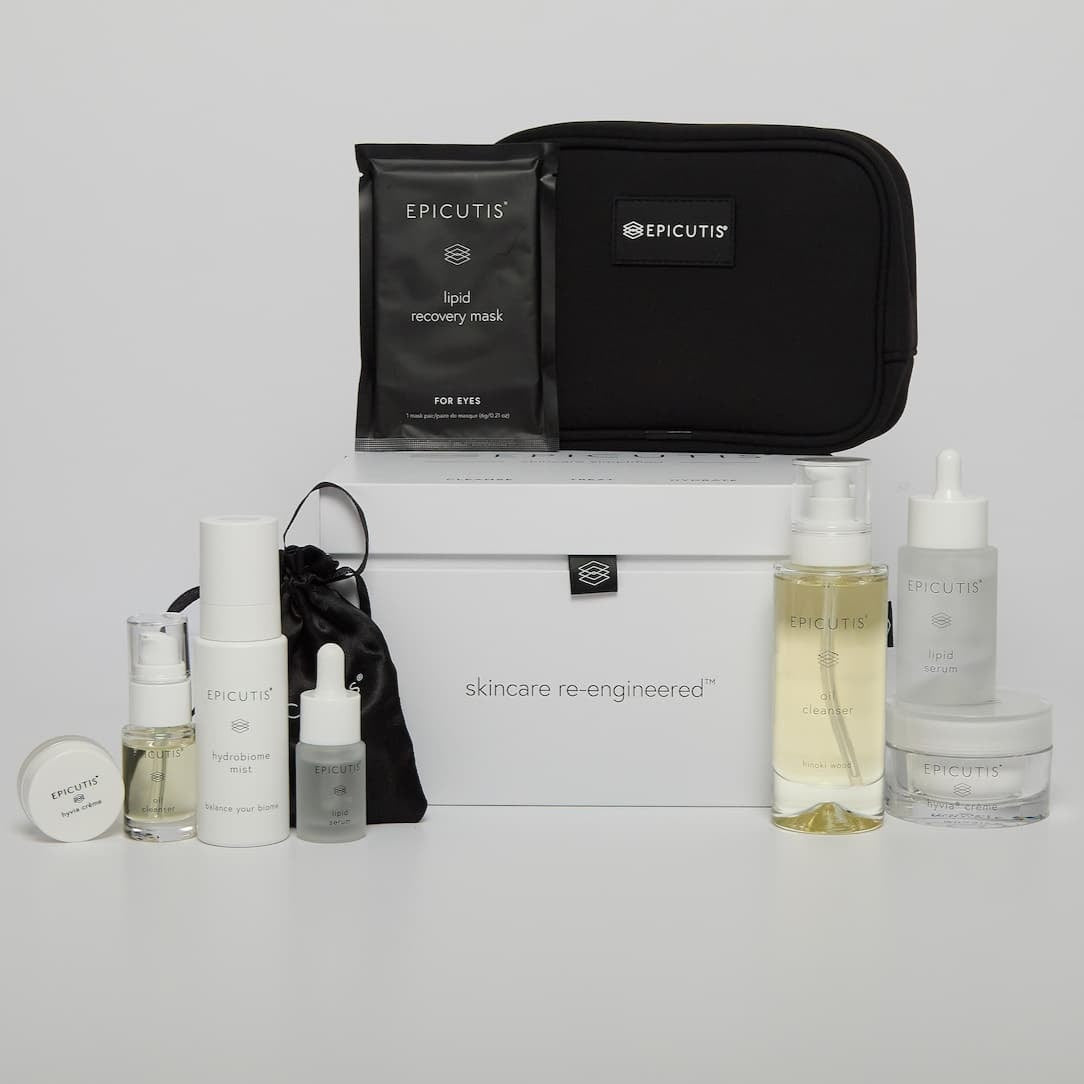 Skincare products and black travel bag on a light gray background